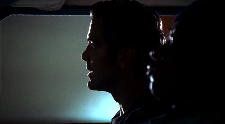 Out Of Sight (1998) movie still: medium — A dark vehicle interior at night with faint light entering through the window. The side profile of a man…
