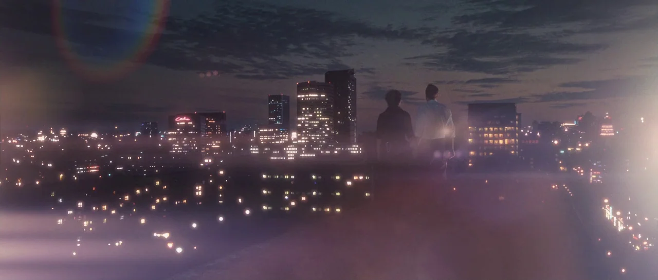 Sound of Noise (2010) movie still: wide — A dark city skyline viewed from a rooftop at night with numerous glowing windows. Two men stand together…