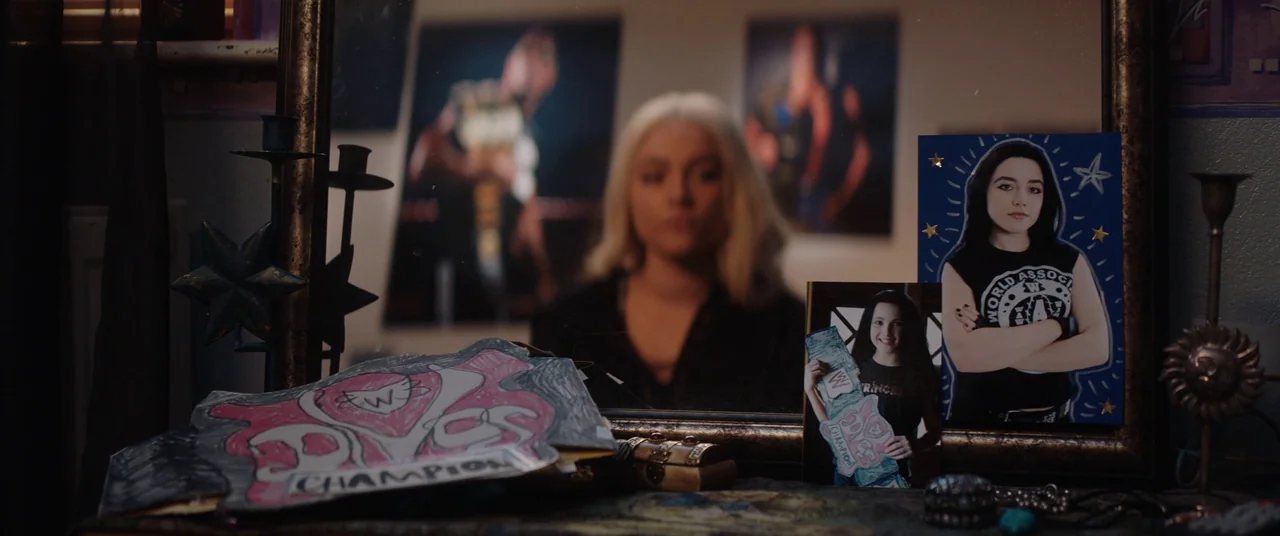 Fighting With My Family (2019) movie still: medium — A dresser surface holds wrestling memorabilia reflected in a large ornate gold-framed mirror. A…