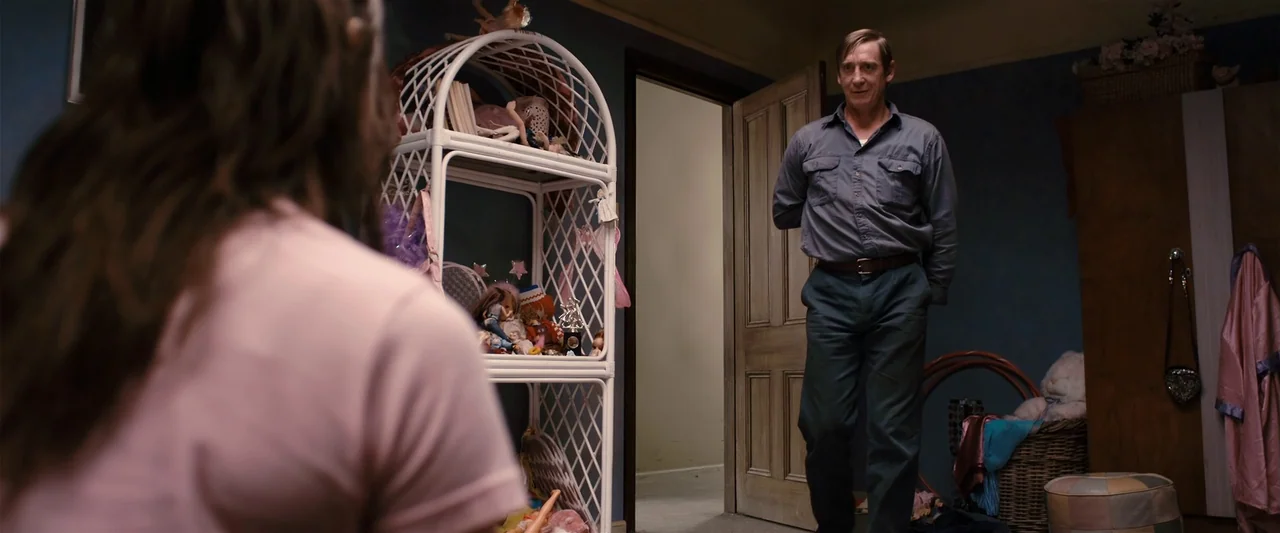 The Loved Ones (2009) movie still: medium — A cluttered child's room with blue walls and a white wicker storage unit. An older man stands in the…