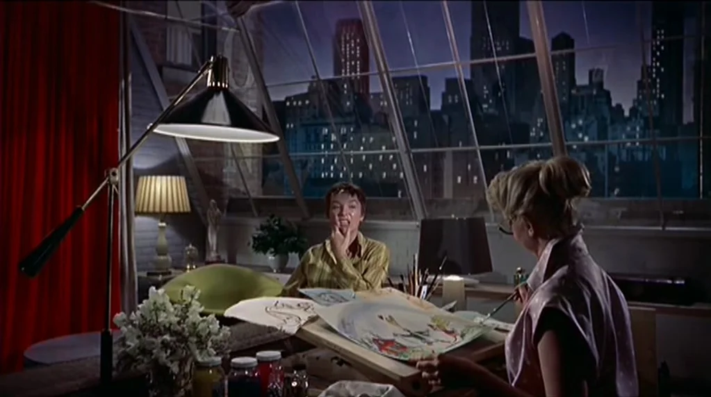 Artists and Models (1955) movie still: medium — An artist's studio loft with large slanted glass windows overlooking a dark city skyline. Two women…