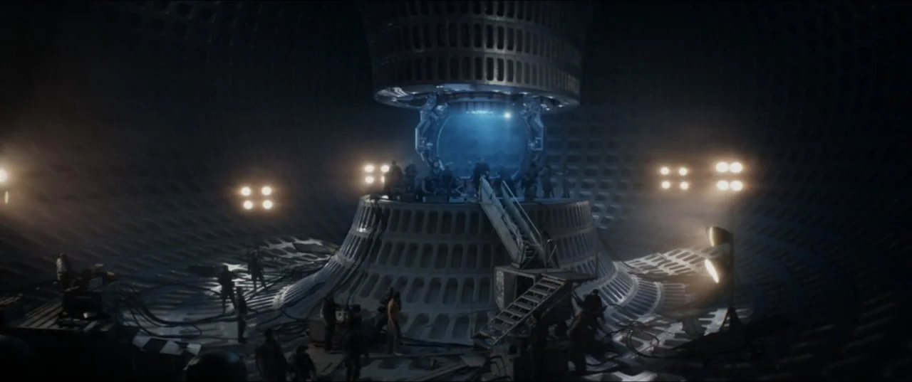 Terminator Genisys (2015) movie still: wide — A vast, cavernous dark industrial space features a large metallic circular reactor or platform.…