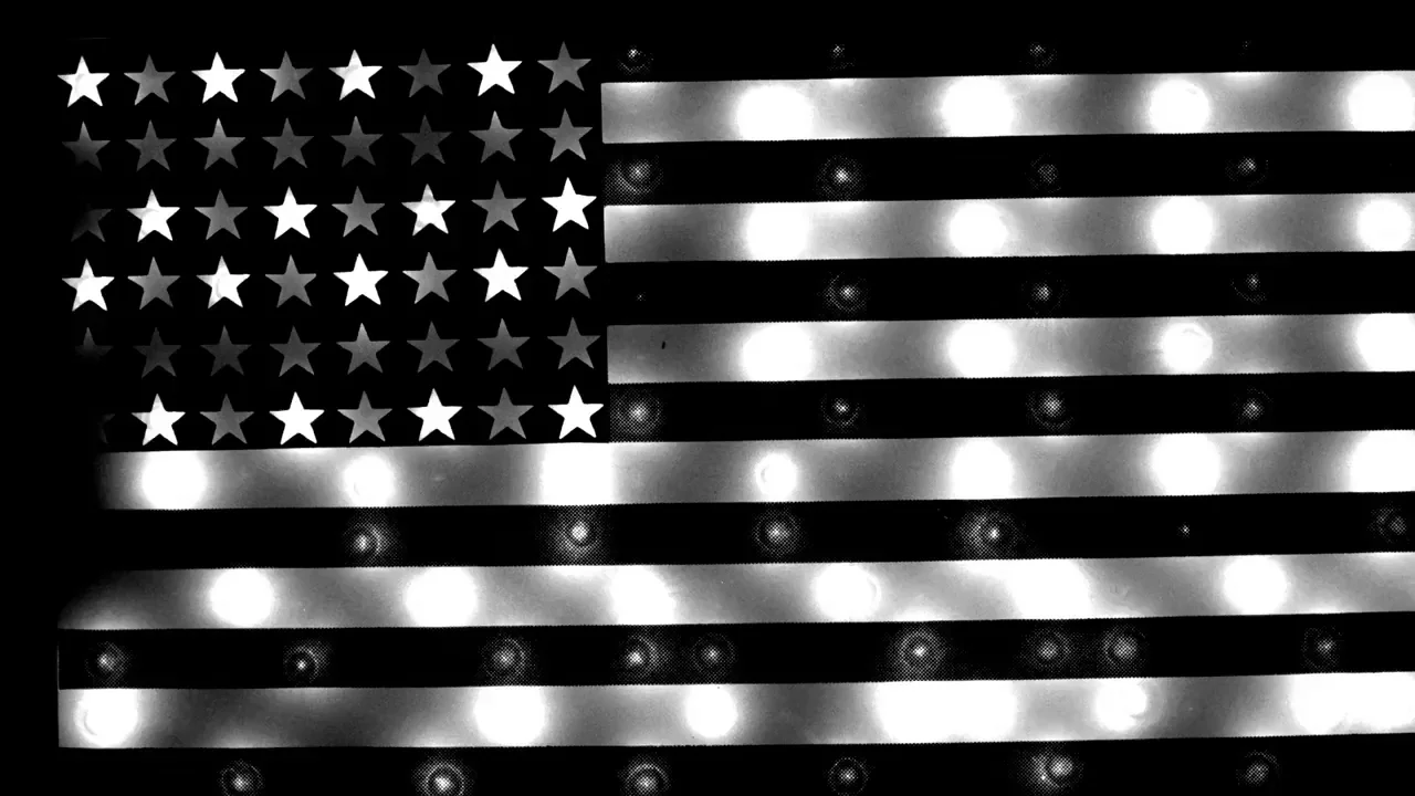 Cruising (1980) movie still: closeup — A decorative American flag wall ornament is constructed from black bars and glowing light bulbs. The stars…