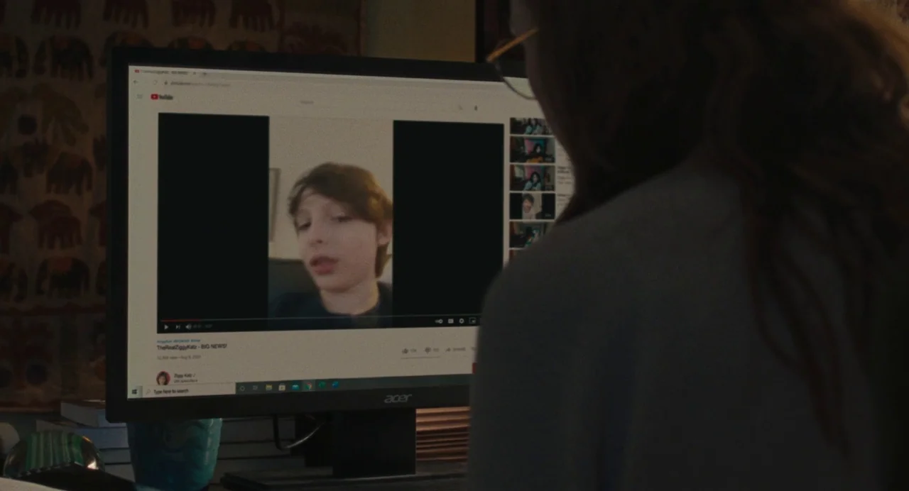 When You Finish Saving The World (2022) movie still: medium — A dimly lit home office space featuring a computer monitor displaying a YouTube video.…