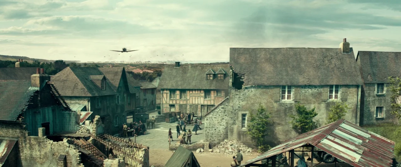 Overlord (2018) movie still: establishing — A European village displays signs of conflict with damaged stonework, rubble, and broken roof tiles.…