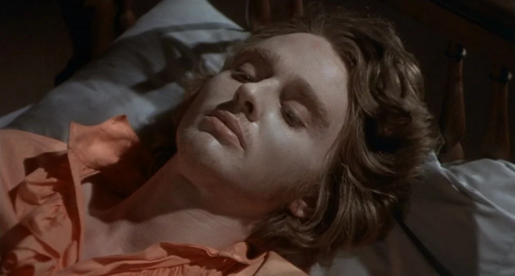 Demons of the Mind (1972) movie still: closeup — A man lies on a pillow in a dimly lit bedroom setting. He is resting with his eyes closed while…