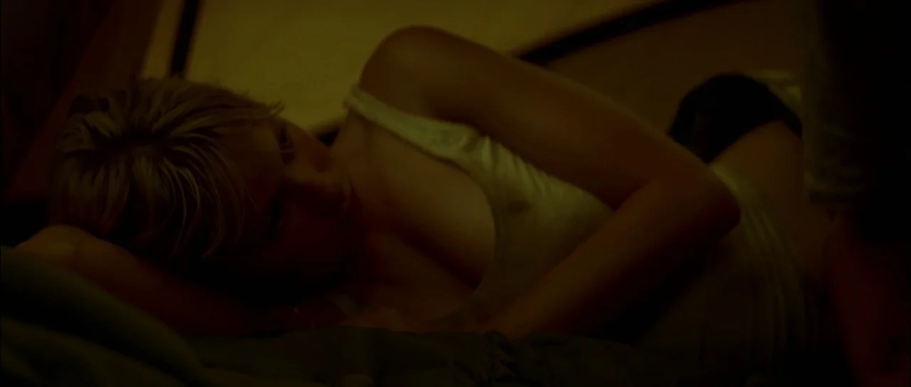 The Ruins (2008) movie still: closeup — The interior of a fabric tent is dimly lit with an amber hue. A young woman lies on her side on a cushioned…