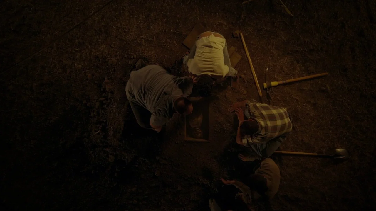 Suburban Gothic (2014) movie still: wide — Four men gather in the darkness around a narrow pit carved into open ground. They kneel in a circle and…