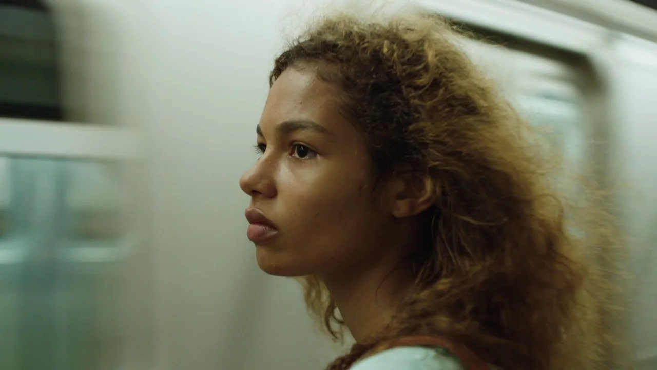 Madeline’s Madeline (2018) movie still: closeup — A view inside a moving public transport car with blurred windows indicating high speed. A young…