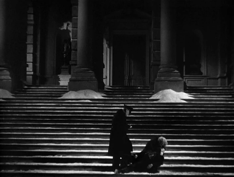 The Roaring Twenties (1939) movie still: wide — A stone staircase leads up to a classical entrance with large columns and statues. One person stands…