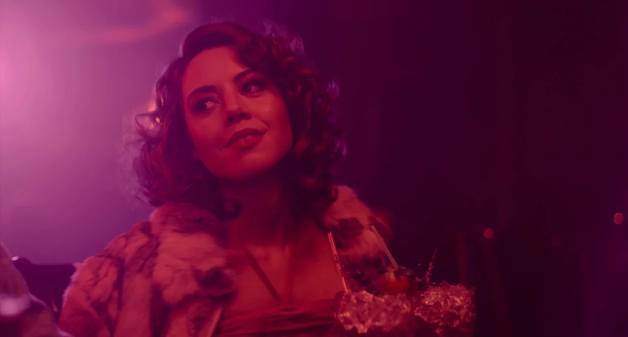An Evening With Beverly Luff Linn (2018) movie still: medium — A dimly lit lounge setting filled with intense magenta-colored light and atmospheric…