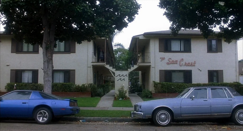 Sideways (2004) movie still: wide — A two-story apartment building features off-white stucco walls and a central outdoor staircase. A blue coupe and…