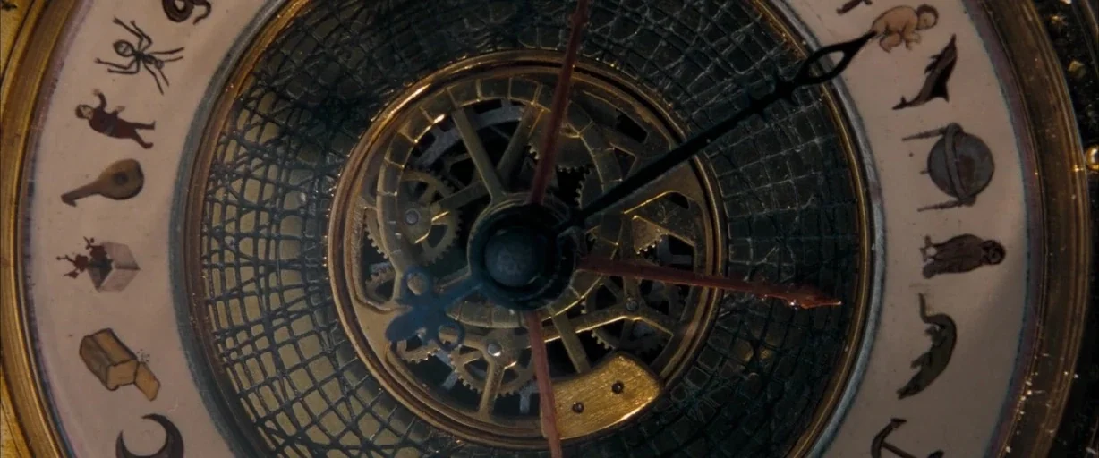 The Golden Compass (2007) movie still: closeup — A close-up view of an ornate, circular mechanical clock face with complex internal gears. Intricate…