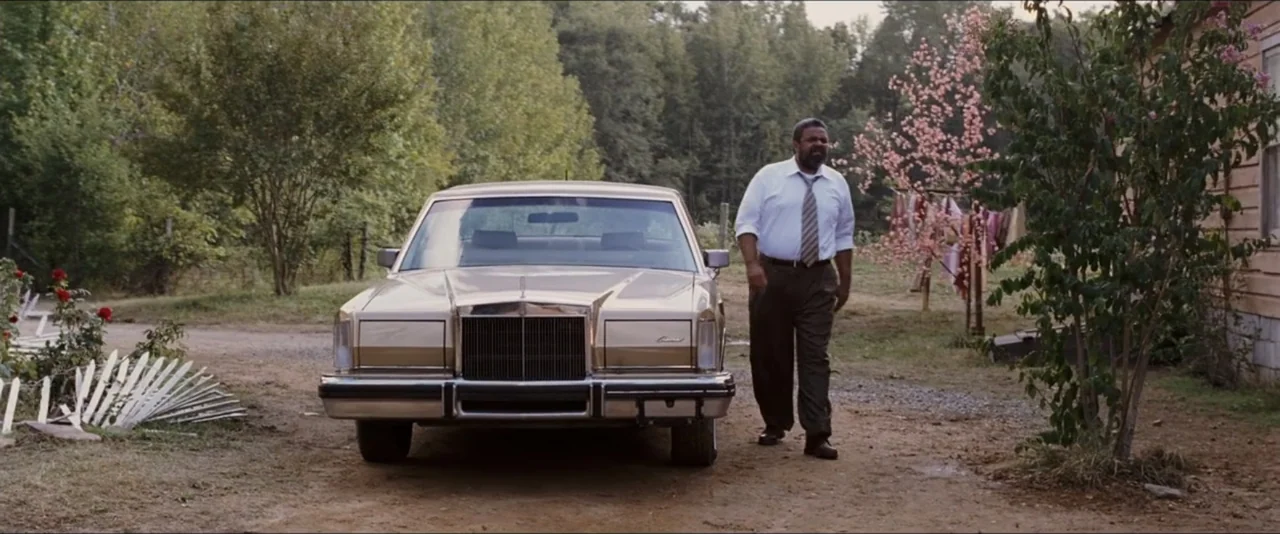 Black Snake Moan (2006) movie still: fullbody — A rural setting with a dirt road, trees, and a parked luxury sedan. A middle-aged man walks…