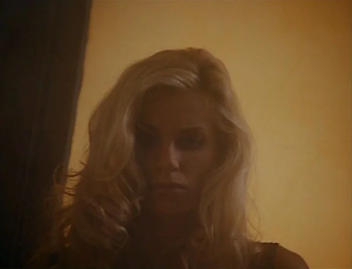 Head of the Family (1996) movie still: closeup — A close portrait of a woman against a plain yellow wall. The subject gazes directly forward while…