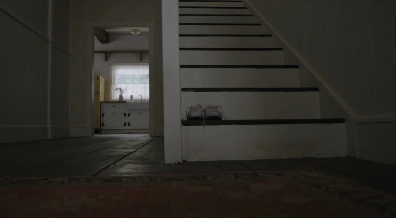 I Am The Pretty Thing That Lives In The House (2016) movie still: wide — A dark hallway with a white staircase contains a pair of white shoes. A…
