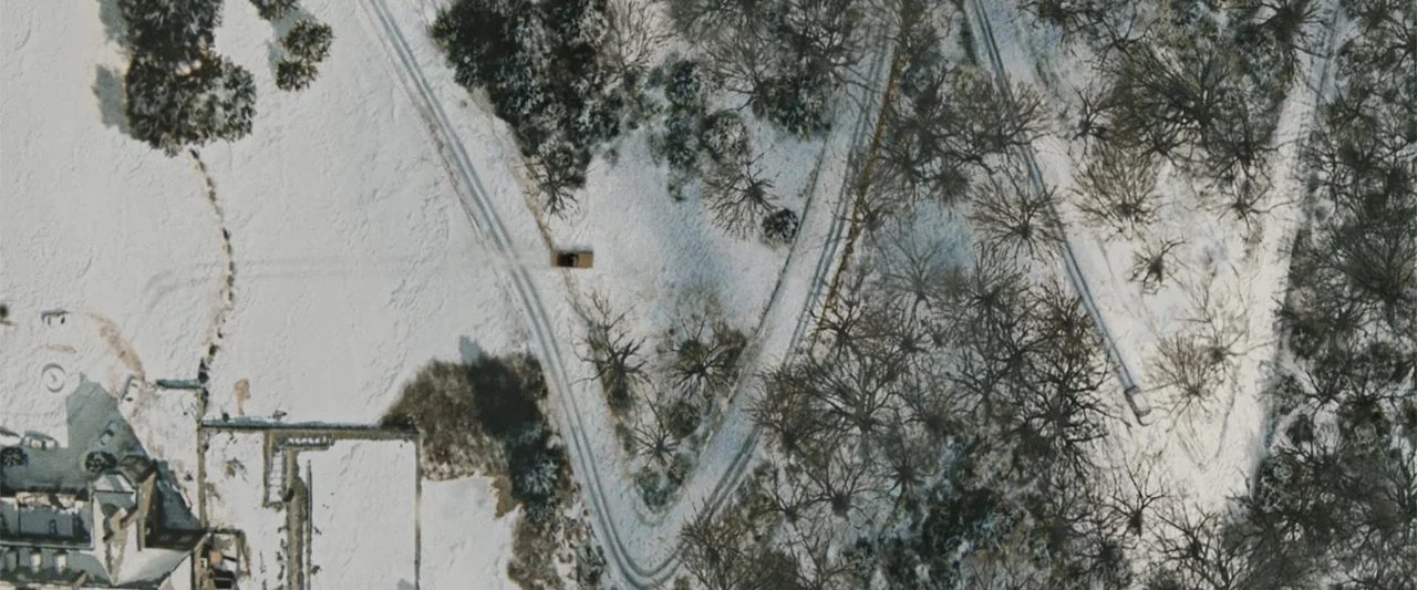 Ghosts of Girlfriends Past (2009) movie still: establishing — A high-angle view looks down at a snowy landscape with sparse, leafless trees. A lone…