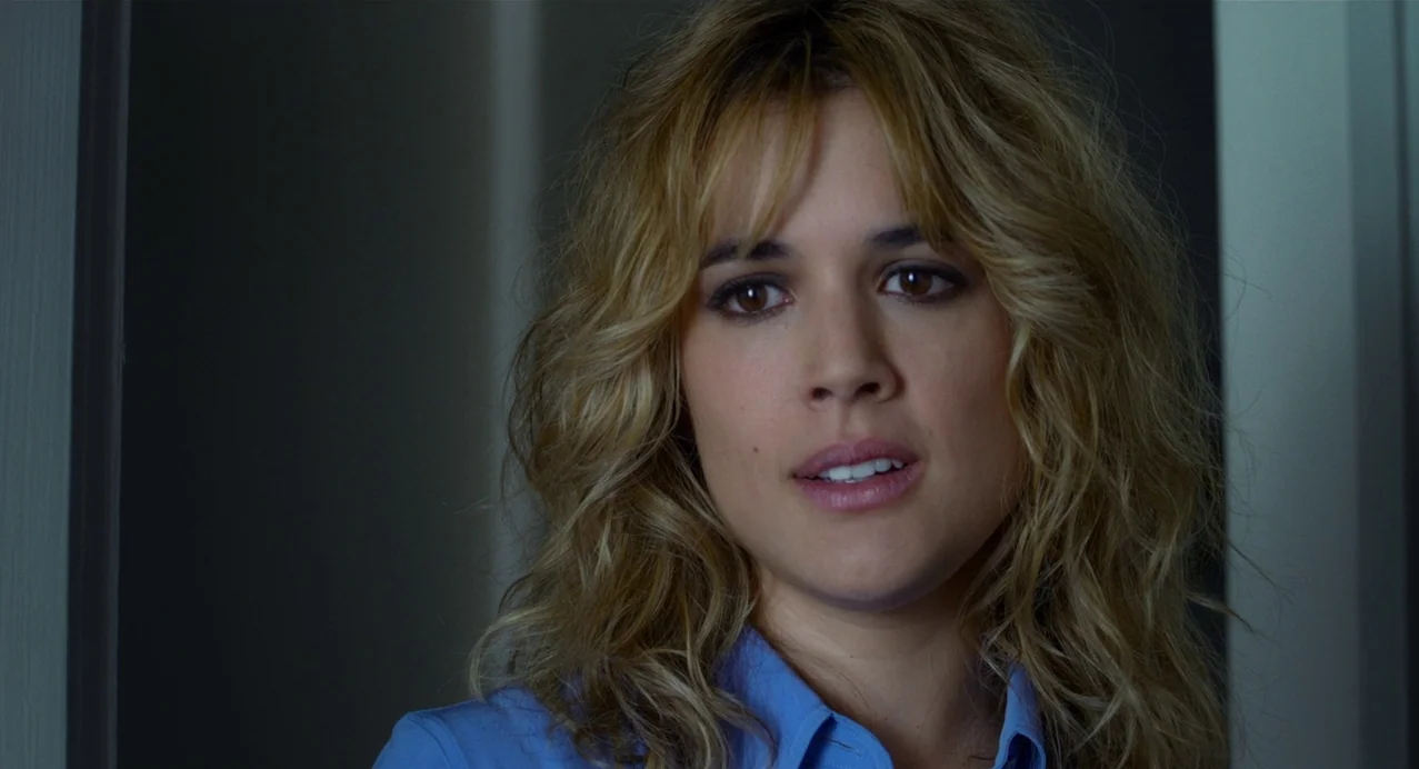 Julieta (2016) movie still: closeup — A woman stands in a dimly lit indoor passage with plain walls. She looks toward the side with her mouth…