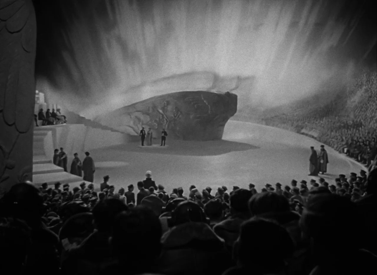 A Matter of Life and Death (1946) movie still: wide — A vast, minimalist stone amphitheater features a large central sculpture under a bright sky. A…