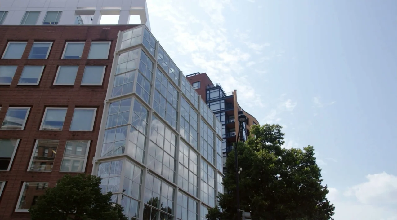 The Divided Soul of America (2019) movie still: establishing — A low angle view shows modern multi-story buildings with brick and glass exterior…