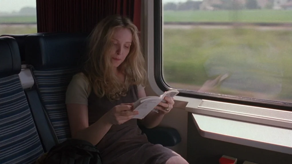 Before Sunrise (1995) movie still: medium — A passenger seat inside a modern train carriage with blue patterned upholstery. A woman sits by the…