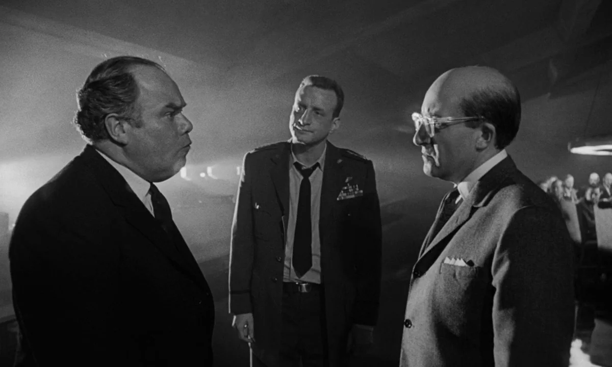 Dr. Strangelove or: How I Learned to Stop Worrying and Love the Bomb (1964) movie still: medium — A dimly lit room with heavy shadows and a hazy…