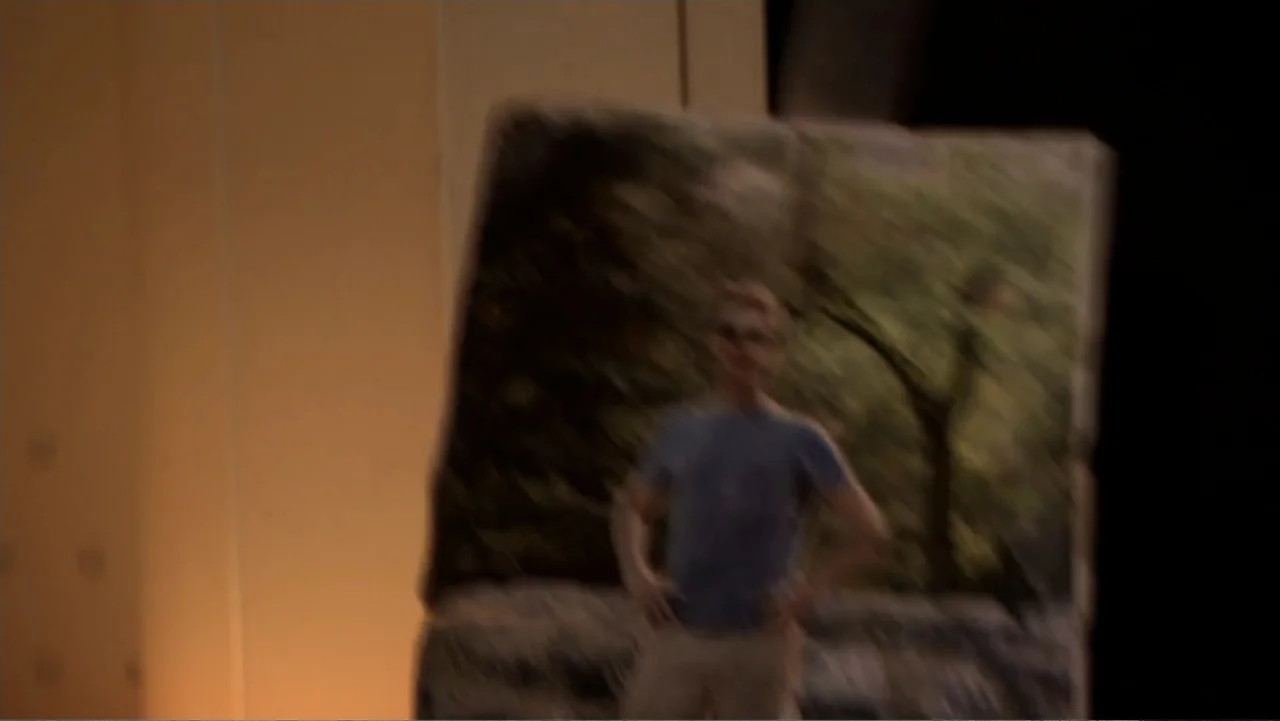 Jeremy Fink and the Meaning of Life (2012) movie still: closeup — An interior space contains a blurry photograph depicting a person in a forest…