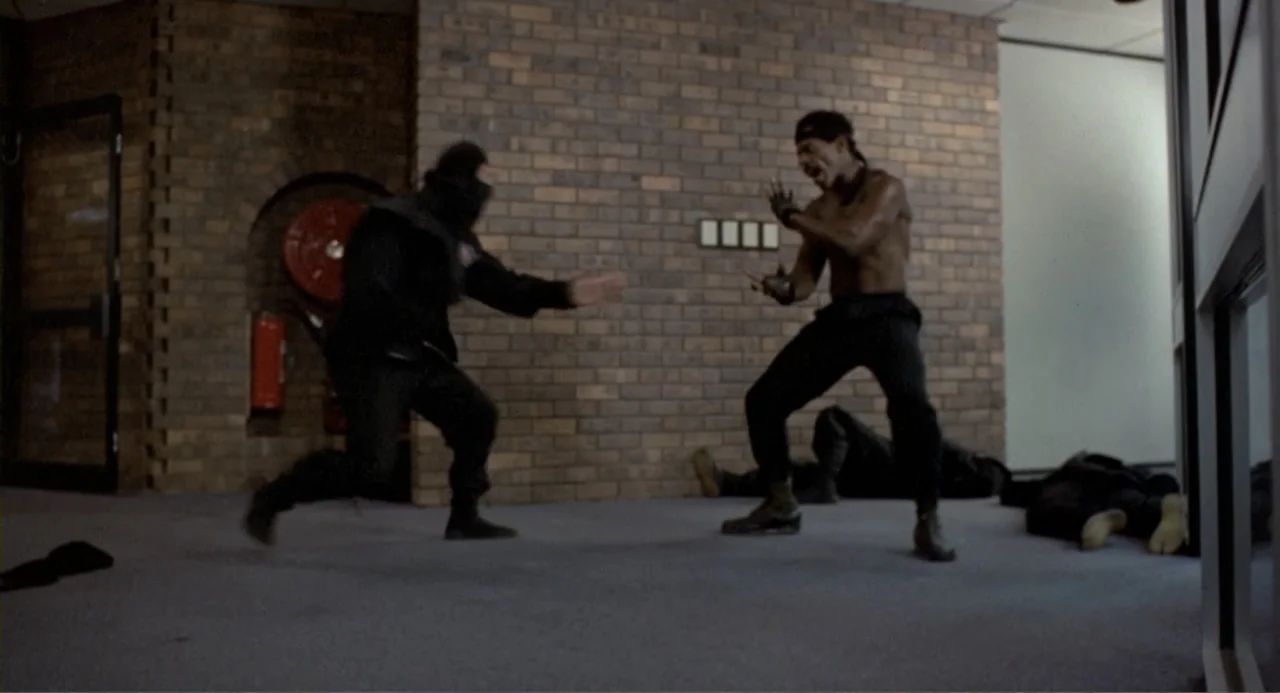 American Ninja 2: The Confrontation (1987) movie still: fullbody — A utilitarian lobby interior features a brown brick accent wall and gray…