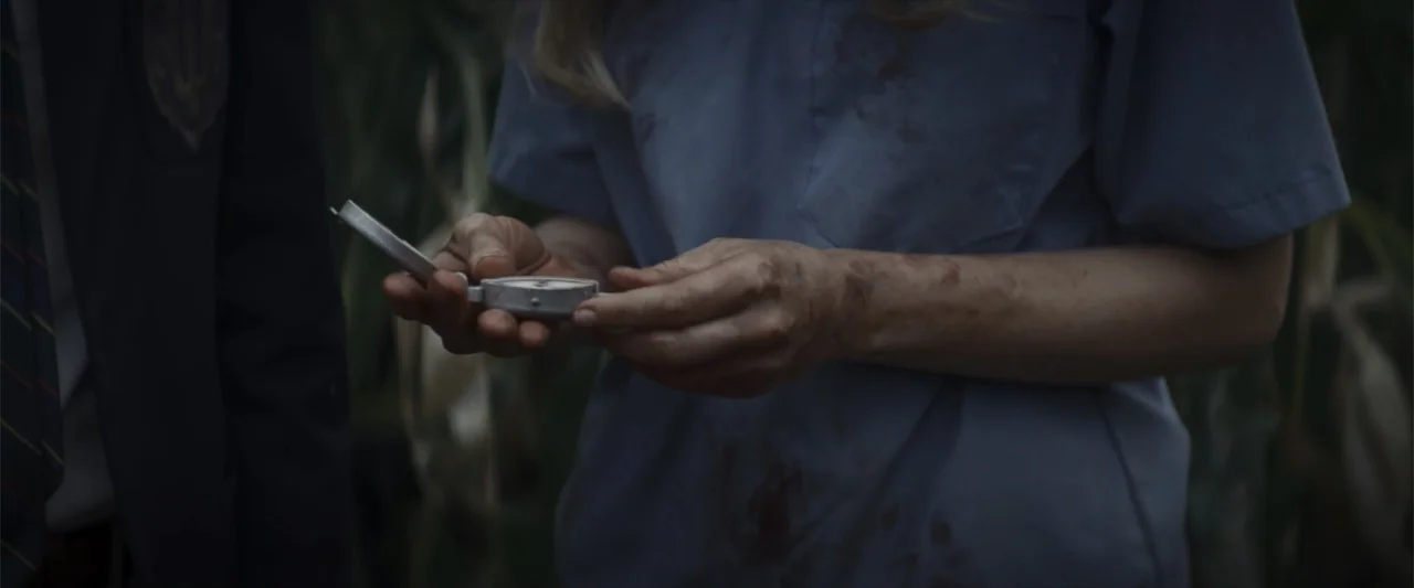 Treblinka's Last Witness (2012) movie still: closeup — A person in dirty scrubs stands in a dense, dark field at night. They examine a small…