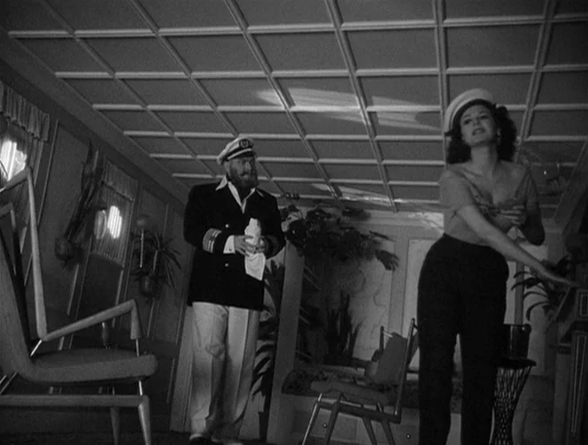 Mr. Arkadin (1955) movie still: fullbody — A ship cabin interior with wood-paneled walls and a geometric grid ceiling design. An older man stands…