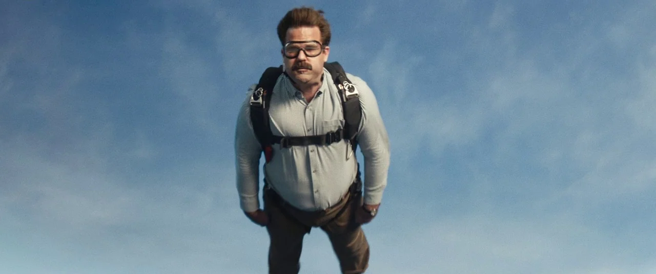 Deadpool 2 (2018) movie still: medium — A man free-falls against a bright, clear blue sky during the day. He wears a parachute harness and goggles…