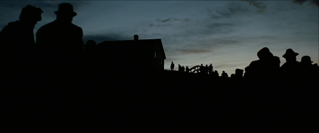 The Assassination Of Jesse James By The Coward Robert Ford (2007) movie still: wide — A rural landscape at dusk features a small house silhouette…