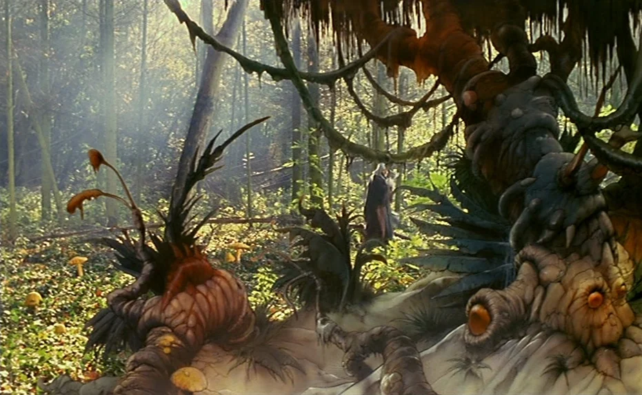 Life Is A Bed of Roses (1983) movie still: wide — A dense woodland clearing contains twisted gnarled root structures resembling creature anatomy…