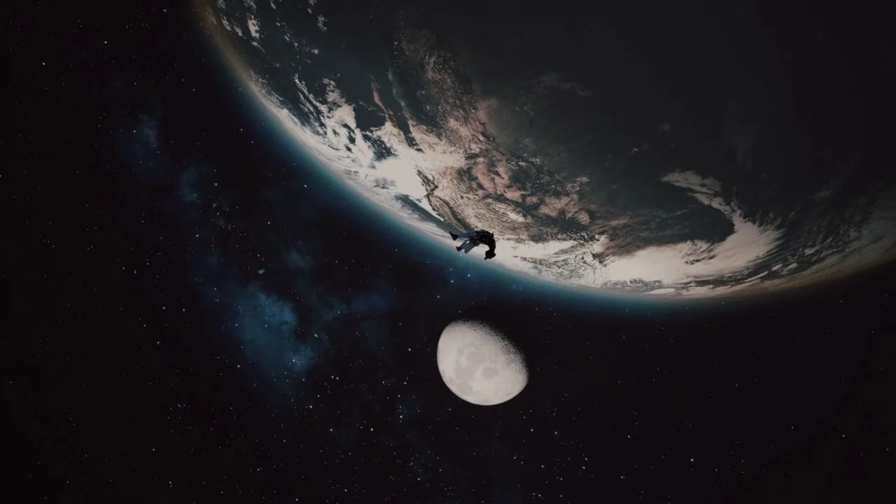 Black is King (2020) movie still: wide — A view of the earth and the moon against the dark expanse of space. A tiny, nondescript object drifts in…
