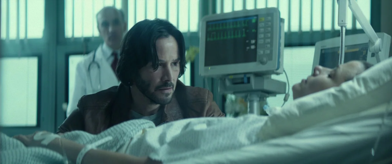 John Wick (2014) movie still: medium — A sterile medical environment features medical monitoring equipment and a bed with a patient. A man in a…