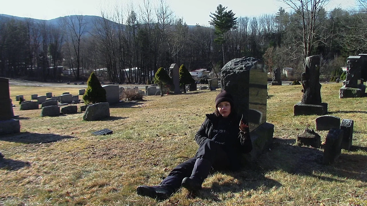 We’re All Going to the World’s Fair (2021) movie still: fullbody — A rural cemetery features numerous headstones scattered across dry,…