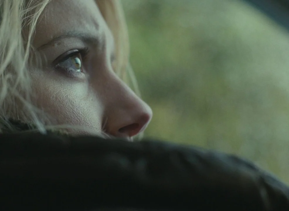 Laurence Anyways (2012) movie still: closeup — A close-up view inside a vehicle with an out-of-focus exterior background. A young woman with blonde…