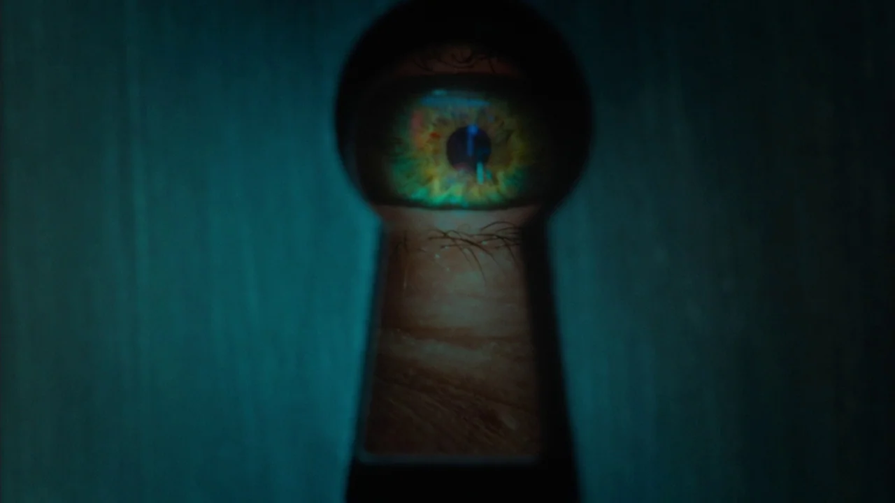 Big Eyes (2014) movie still: closeup — A dark wooden door surrounds a central keyhole that acts as a frame. One human eye looks directly through the…