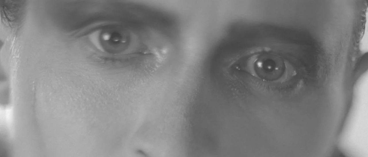 She Is Conann (2023) movie still: closeup — A close-up view focuses on a pair of eyes looking directly forward. The skin texture around the eyes is…