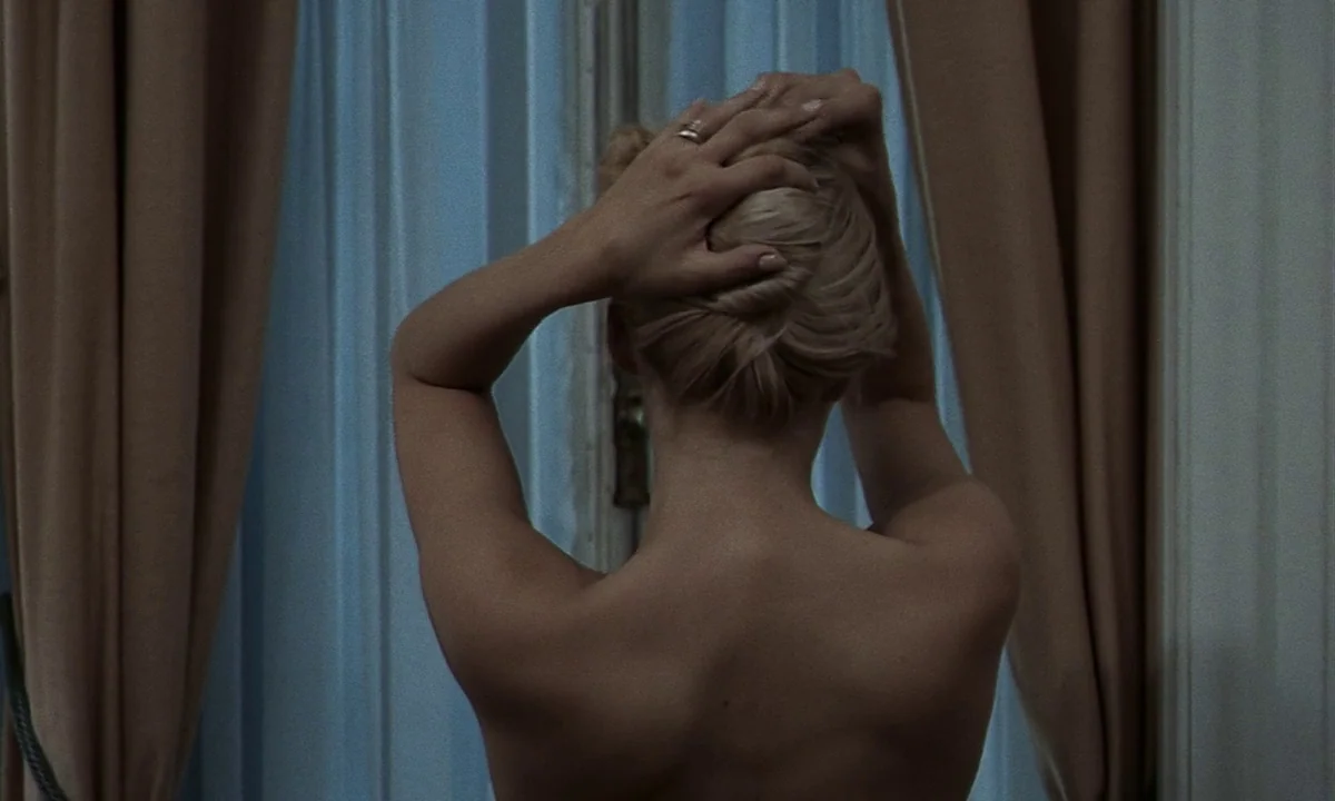 Daughters of Darkness (1971) movie still: medium — A room features a large window covered by light curtains and beige fabric drapes. A shirtless…