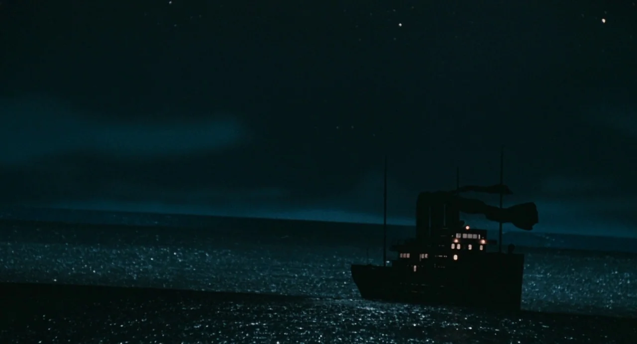 And The Ship Sails On (1983) movie still: establishing — A dark ship silhouette travels across a vast, moonlit ocean under a star-filled sky. The…