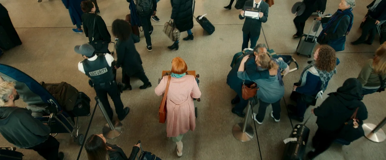 Three Thousand Years of Longing (2022) movie still: wide — A busy airport terminal with numerous travelers moving across a large concrete tiled…