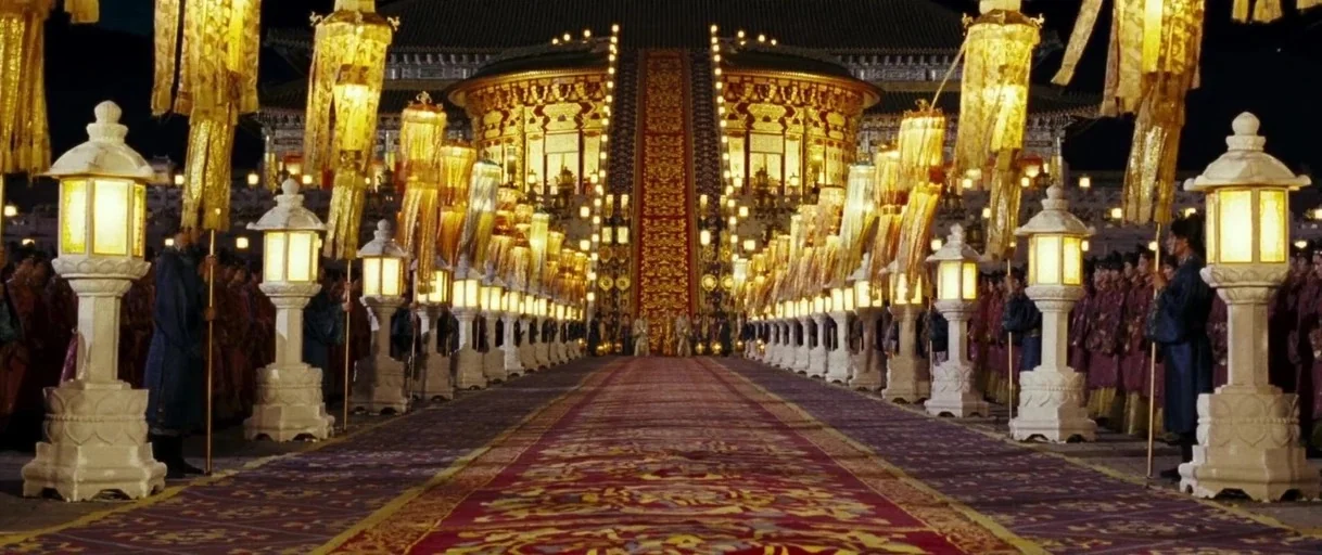 Curse of the Golden Flower (2006) movie still: establishing — A long, symmetrical stone path leads toward a massive illuminated imperial building at…