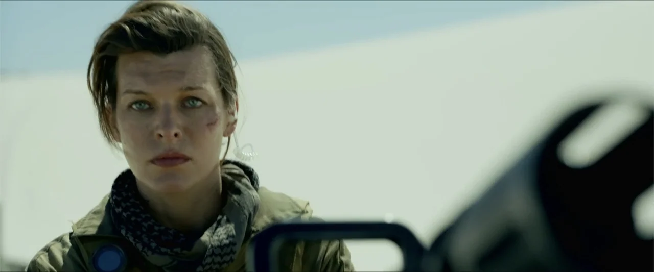 Monster Hunter (2020) movie still: medium — A desolate white sand landscape stretches out behind the character under a bright sky. A woman wearing a…