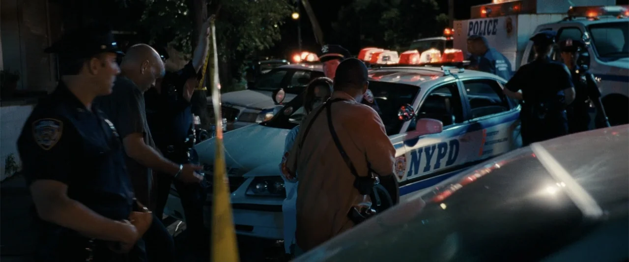 Cop Out (2010) movie still: medium — A dark urban environment at night with an NYPD patrol car parked near yellow tape. Several police officers…