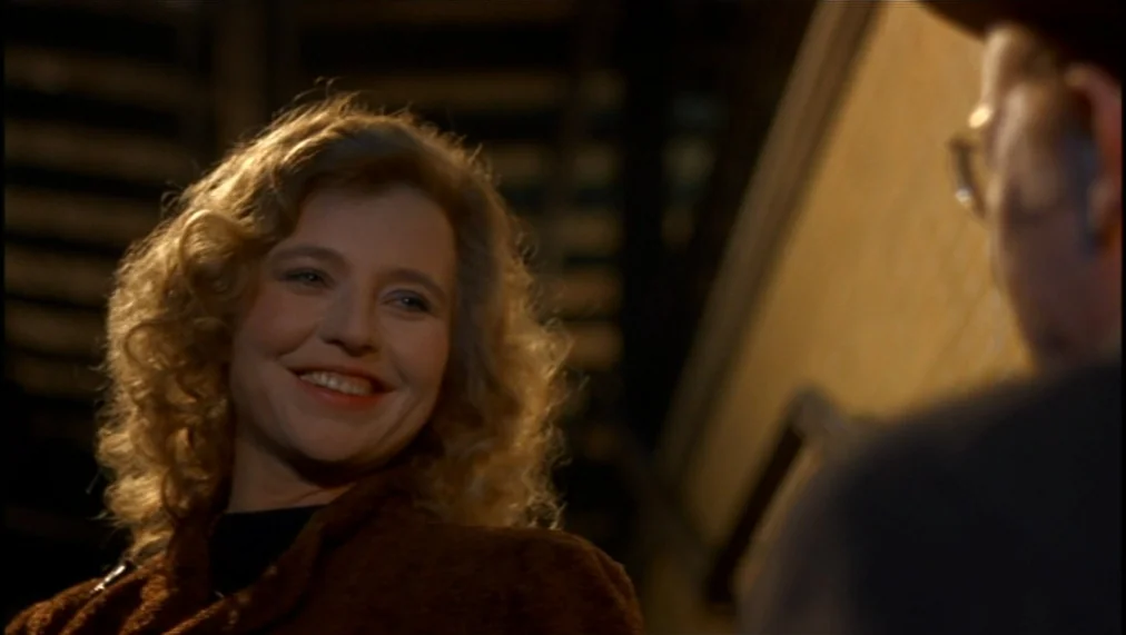 The Marriage of Maria Braun (1979) movie still: closeup — A woman stands on a dark fire escape at night with a man partially visible. She smiles at…