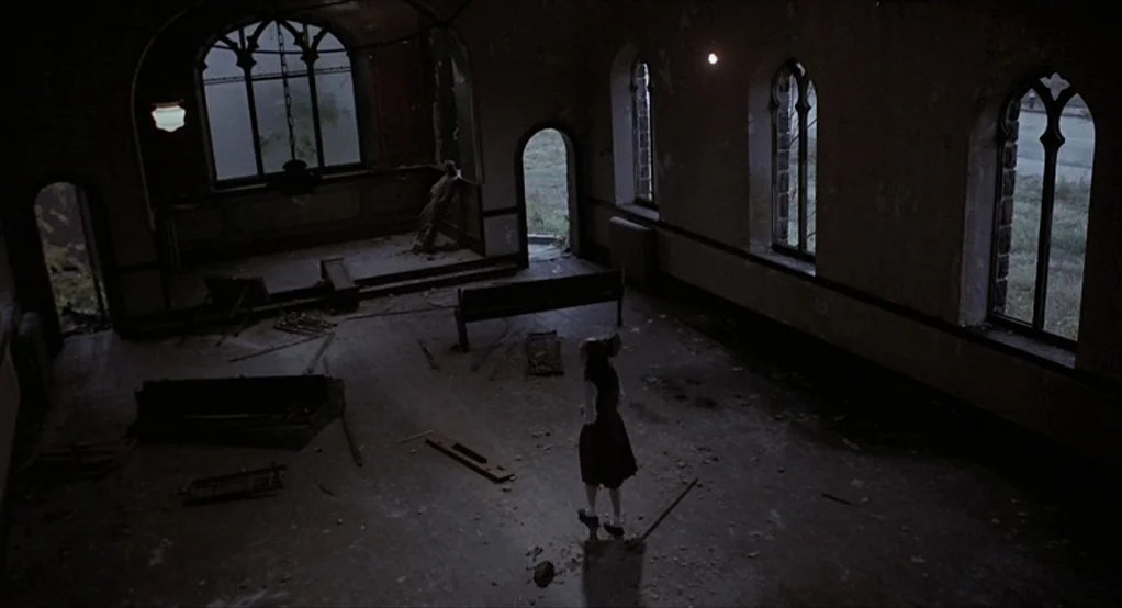 Puzzle of a Downfall Child (1970) movie still: wide — A derelict building interior with debris-covered floorboards and arched stained glass windows.…