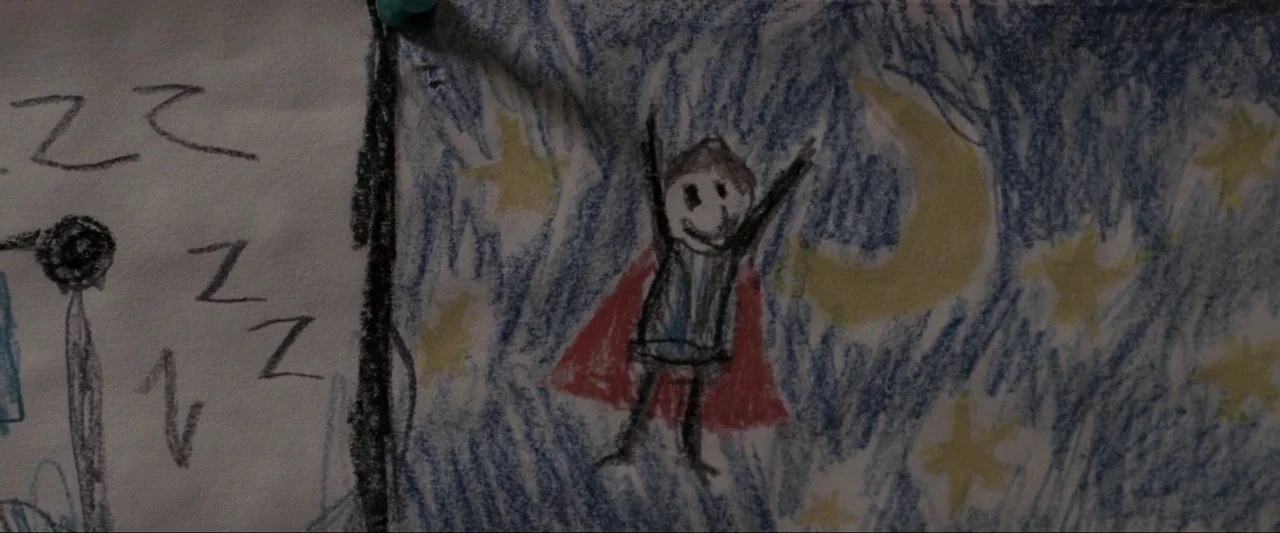 Insidious (2010) movie still: closeup — A children's crayon drawing on paper is pinned to a wall surface. The drawing shows a stick figure with a…