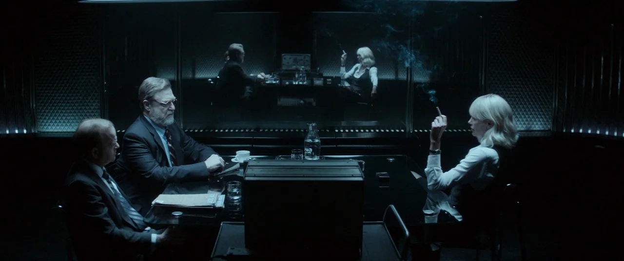 Atomic Blonde (2017) movie still: wide — A dark, modern interior with a large glass table and a reflective partition wall. Three people are seated…