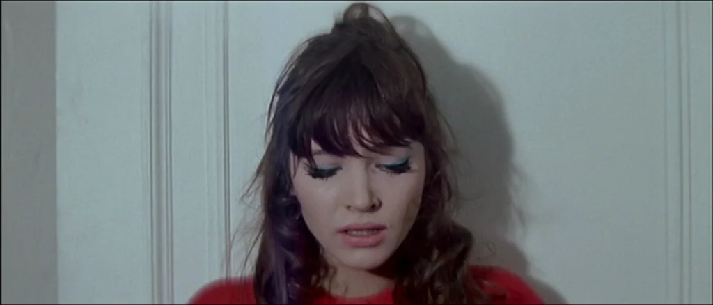 Une Femme Est Une Femme (A Woman Is a Woman) (1961) movie still: closeup — A woman stands before a plain white wall with vertical architectural…